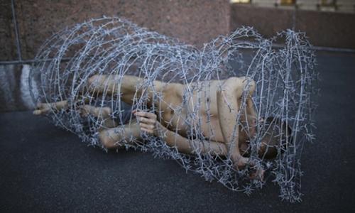 Pyotr Pavlensky lies on the ground in barbwire - photo Reuters